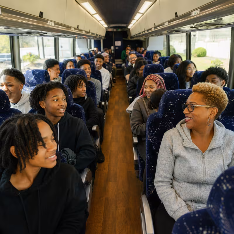 Group boarding a white charter bus for School Transportation transportation in Oakland